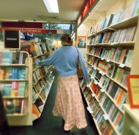 a woman walking down the aisle of a book store